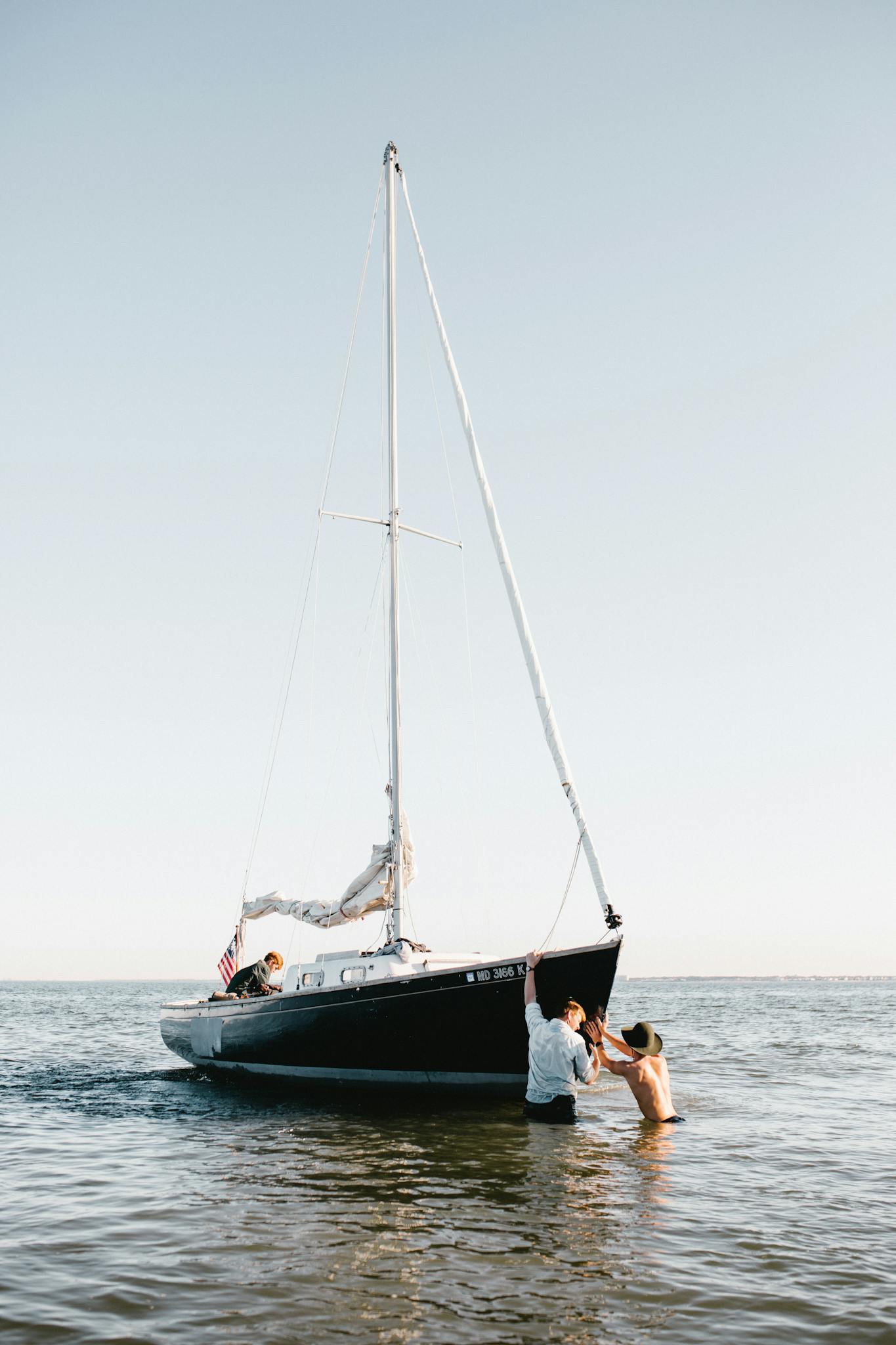 Man in Black Shorts Sitting on White Boat